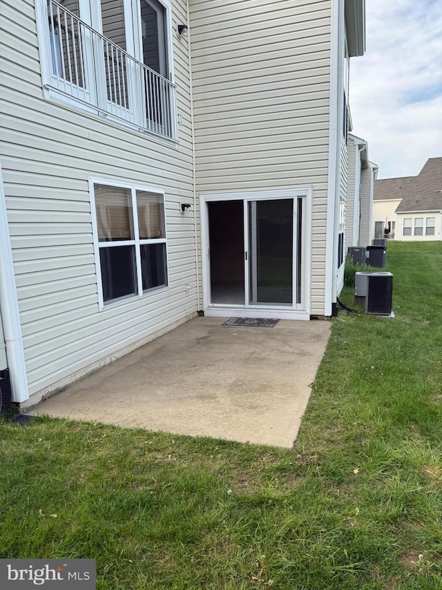rear view of house with a lawn, central AC, and a patio area