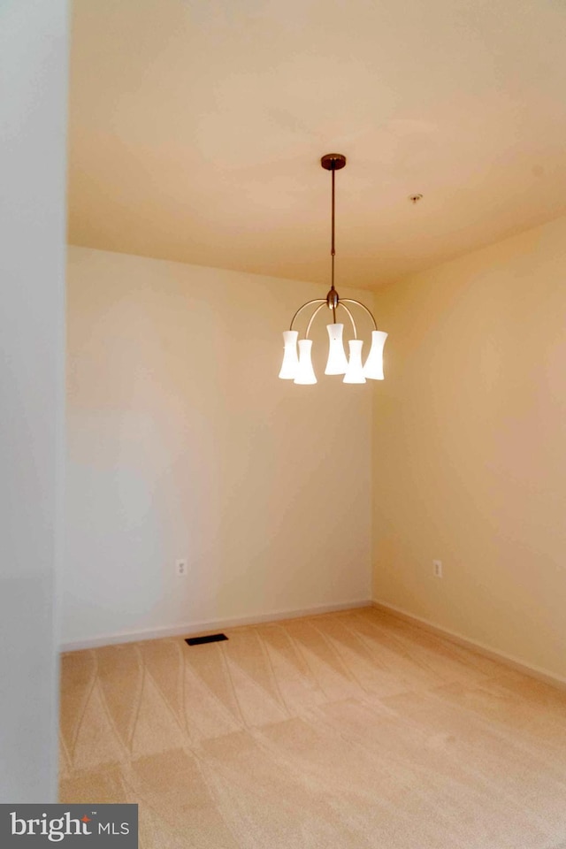 unfurnished room featuring an inviting chandelier, visible vents, baseboards, and light carpet