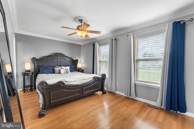 bedroom with visible vents, ceiling fan, baseboards, ornamental molding, and light wood finished floors