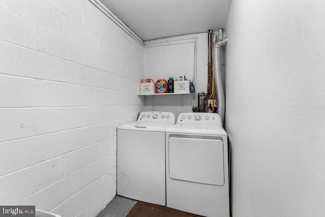 washroom with washer and clothes dryer, laundry area, and concrete block wall
