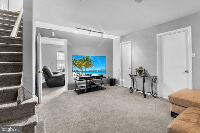carpeted living room with track lighting and stairs