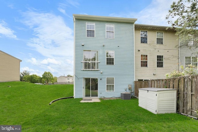 back of property with fence, central air condition unit, and a lawn