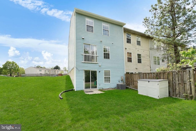 rear view of property featuring central air condition unit, a yard, and fence