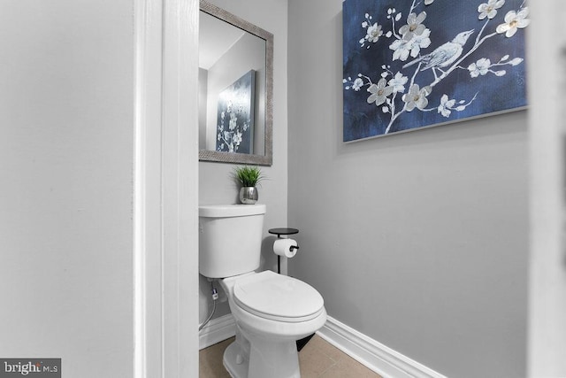 bathroom with baseboards, tile patterned floors, and toilet