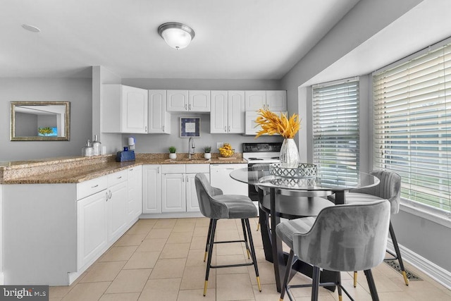 kitchen featuring white appliances, white cabinets, a peninsula, and a sink