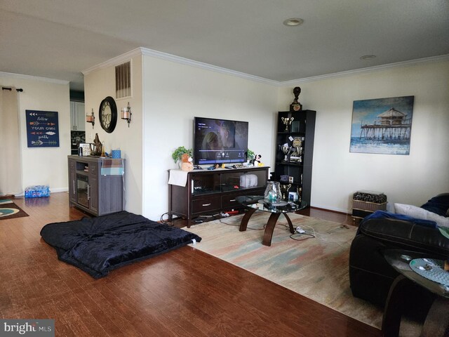 living room featuring visible vents, wood finished floors, baseboards, and ornamental molding