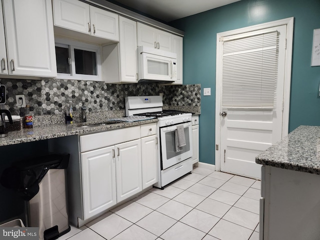 kitchen with a sink, white appliances, white cabinetry, backsplash, and light tile patterned floors