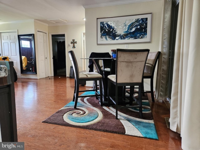 dining room with attic access, wood finished floors, and ornamental molding