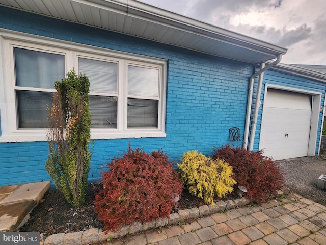 view of side of home with an attached garage and brick siding