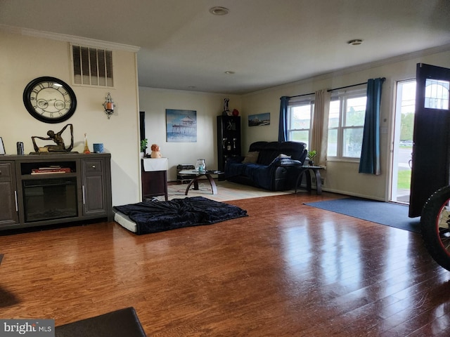 living room with crown molding, visible vents, and wood finished floors