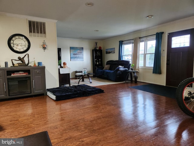 living area featuring crown molding, visible vents, and wood finished floors