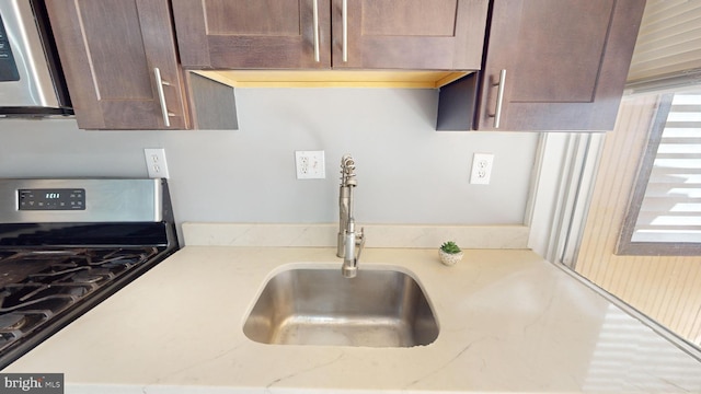 903 K St NE, Washington, DC 20002 - kitchen with light stone countertops, stainless steel range with gas cooktop, dark brown cabinetry, and a sink