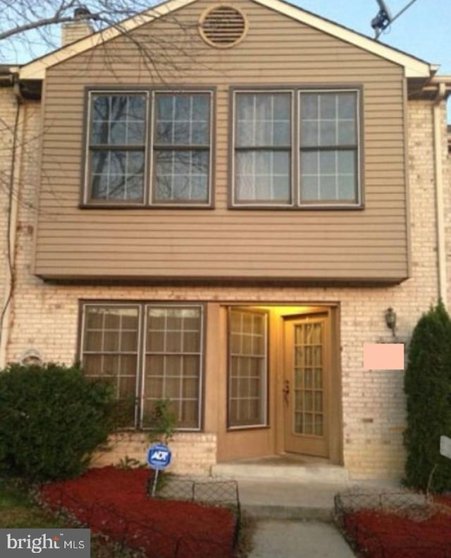 view of front of home with a chimney and brick siding