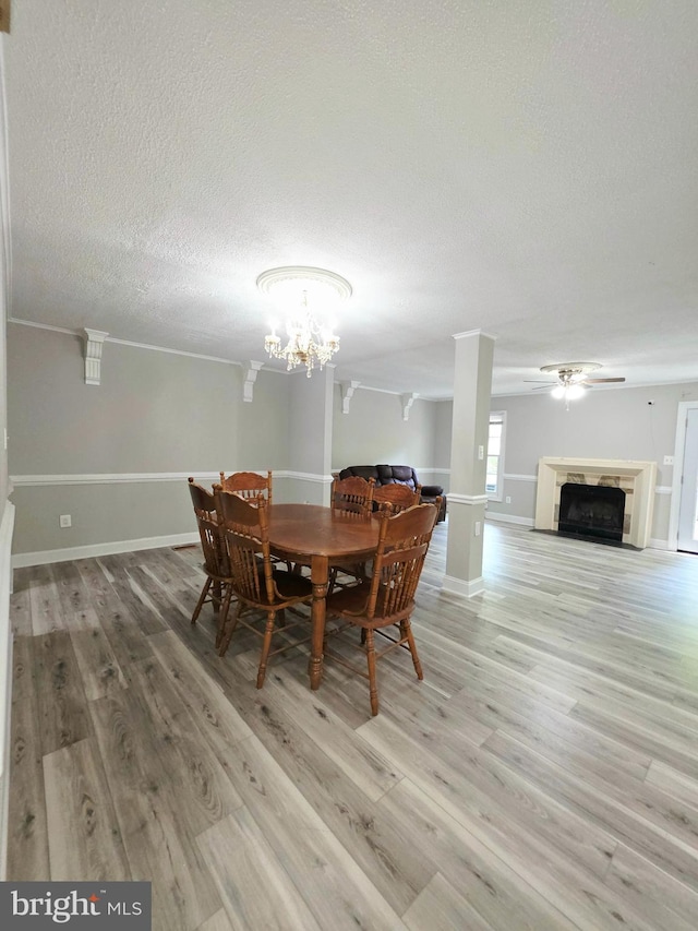 dining space featuring a fireplace, a textured ceiling, baseboards, and light wood-style floors