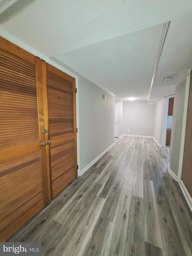 hall with crown molding, baseboards, visible vents, and wood finished floors