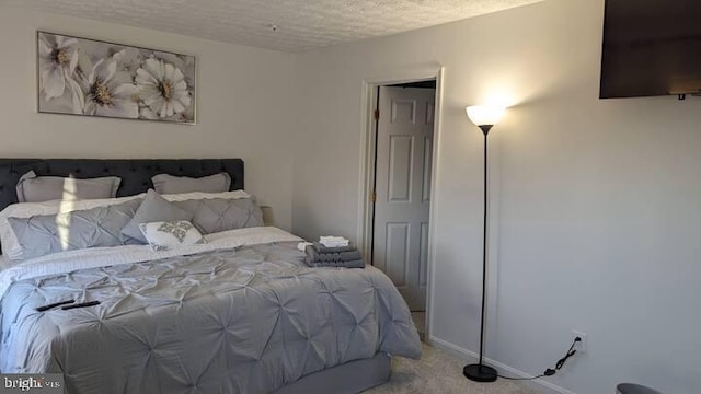 bedroom with baseboards, a textured ceiling, and carpet