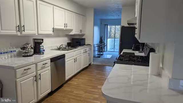 kitchen featuring a sink, white cabinets, wood finished floors, and black appliances