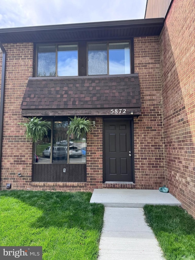 property entrance featuring brick siding and a yard