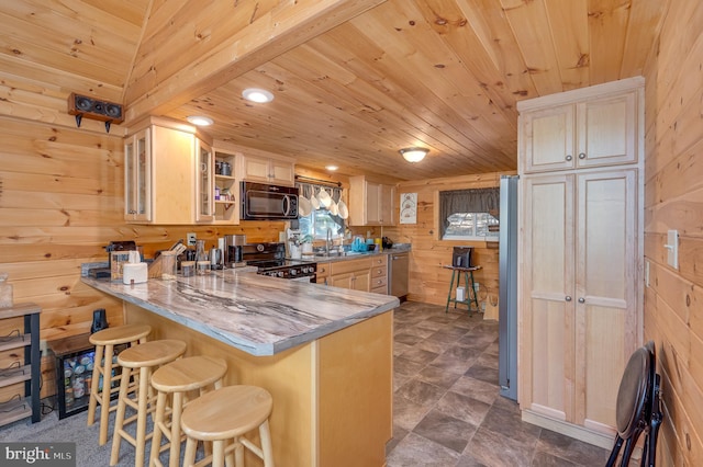 kitchen featuring wooden walls, glass insert cabinets, black appliances, and a peninsula