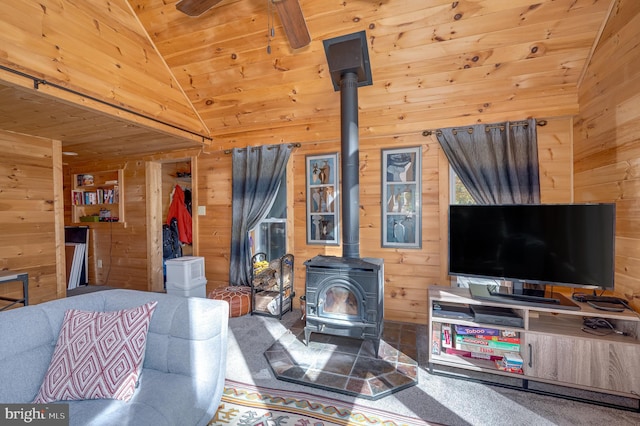 living room with wood walls, vaulted ceiling, a wood stove, and wooden ceiling