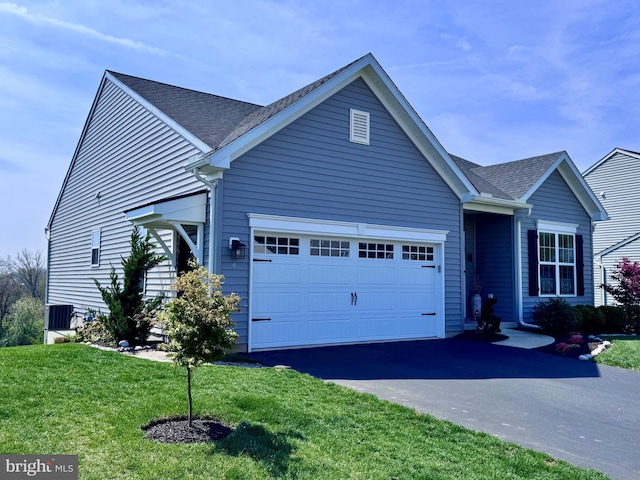 view of front facade with a front yard, roof with shingles, aphalt driveway, and a garage