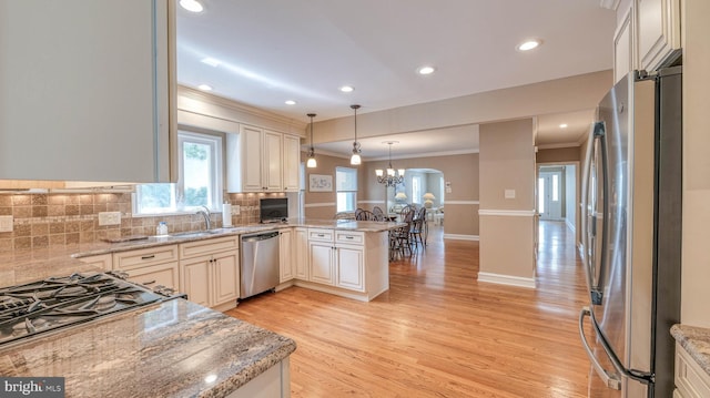 107 S Dover Ave, Atlantic City, NJ 08401 - kitchen with crown molding, light wood-style floors, stainless steel appliances, decorative light fixtures, and a peninsula