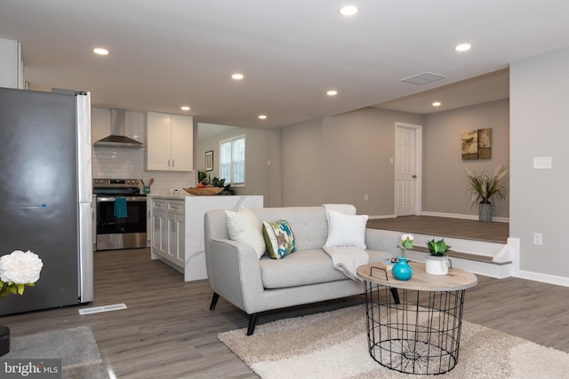 living room with baseboards, recessed lighting, wood finished floors, and visible vents