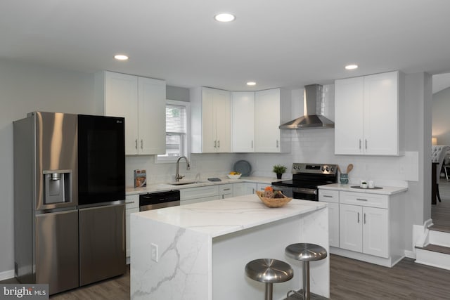 kitchen featuring wall chimney range hood, stainless steel appliances, dark wood-style flooring, and a sink