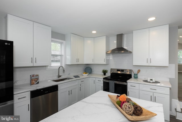 kitchen with wall chimney range hood, stainless steel appliances, white cabinetry, and a sink