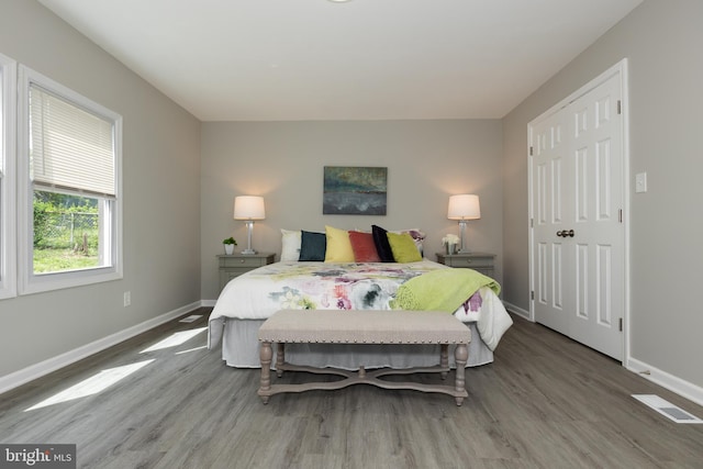bedroom with baseboards, wood finished floors, and visible vents