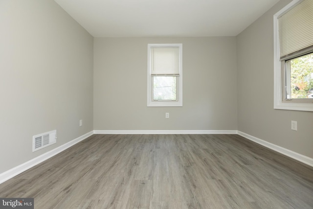 empty room with baseboards, wood finished floors, and visible vents