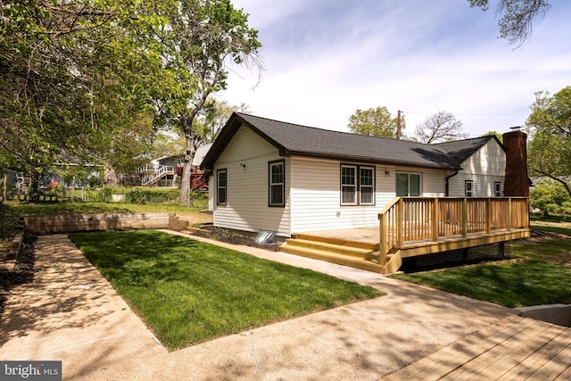 rear view of house featuring a lawn and a deck
