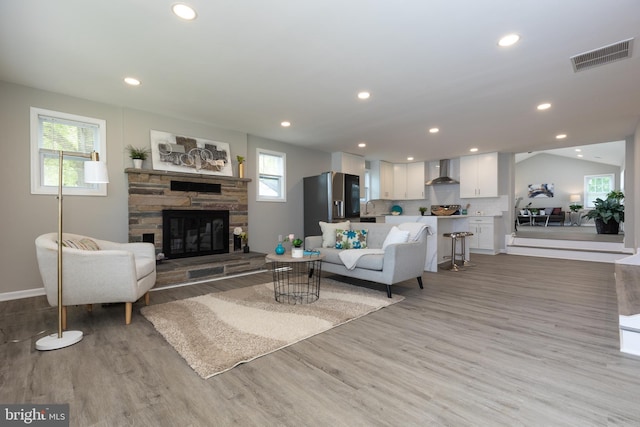 living room with visible vents, a fireplace, baseboards, recessed lighting, and light wood finished floors