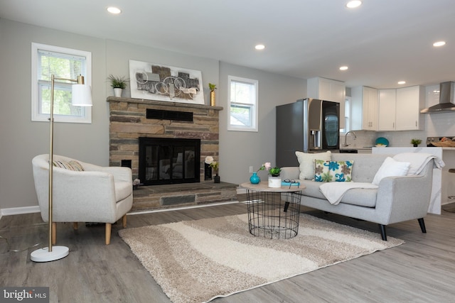 living room with recessed lighting, baseboards, a fireplace, and light wood-type flooring