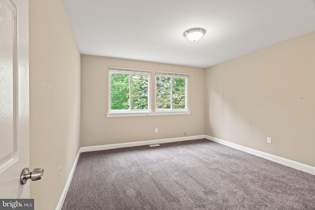 carpeted empty room featuring baseboards