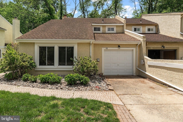 multi unit property with stucco siding, driveway, a garage, and roof with shingles