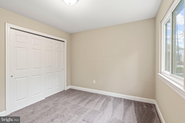 unfurnished bedroom with carpet, baseboards, and a closet