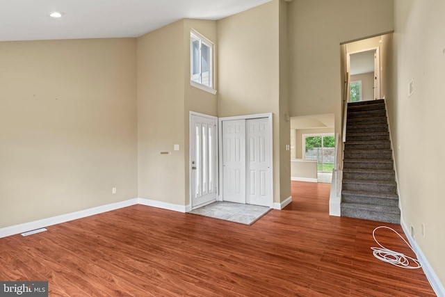 entrance foyer featuring a high ceiling, wood finished floors, baseboards, and stairs