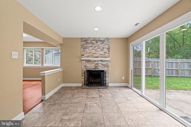unfurnished living room featuring healthy amount of natural light, a fireplace, baseboards, and recessed lighting
