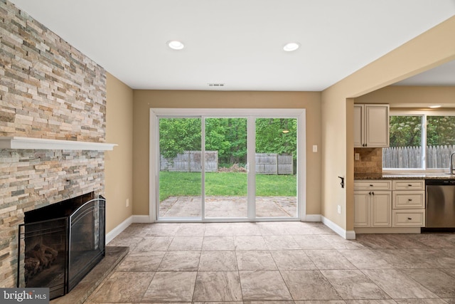 unfurnished living room with plenty of natural light, a fireplace, baseboards, and recessed lighting
