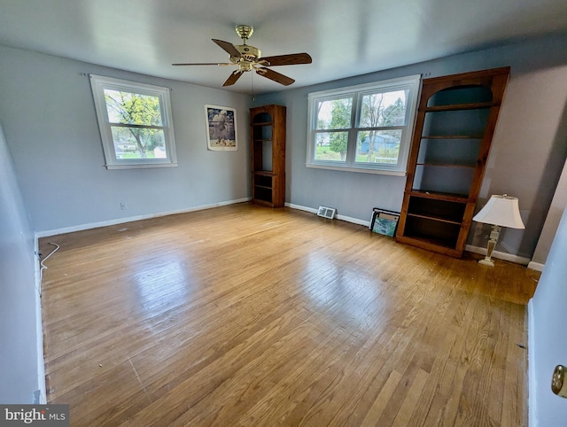 interior space featuring a wealth of natural light, wood finished floors, ceiling fan, and visible vents