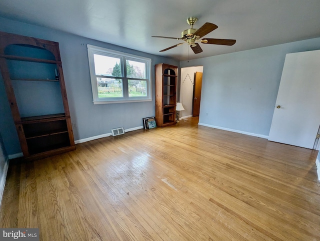 interior space featuring baseboards, visible vents, wood finished floors, and a ceiling fan