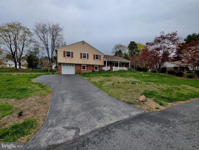 split level home featuring driveway, a front lawn, brick siding, and an attached garage