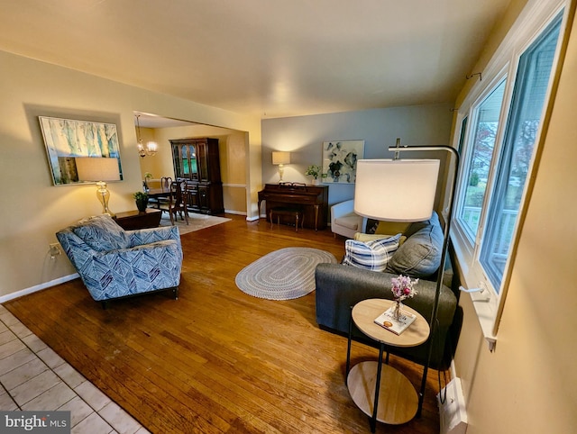 tiled living room featuring a notable chandelier and baseboards