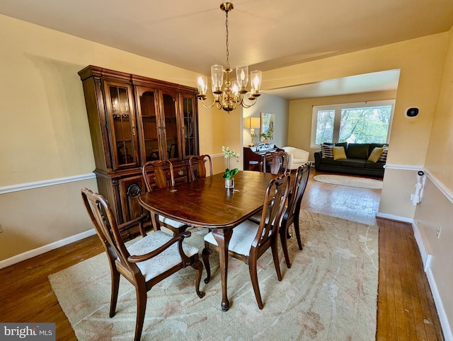 dining space with light wood finished floors, a chandelier, and baseboards