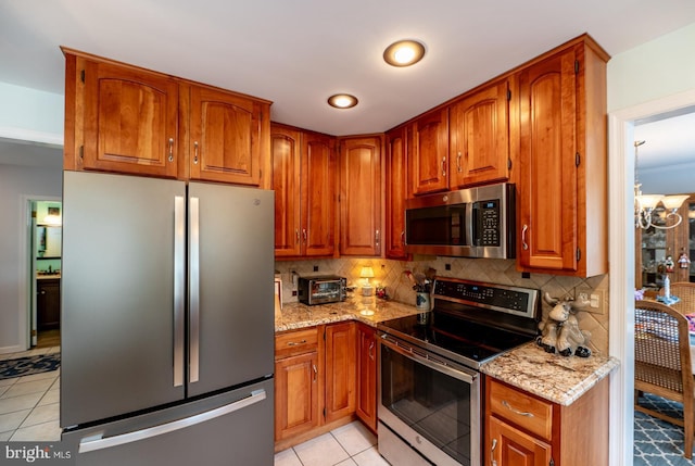 kitchen with backsplash, light tile patterned floors, light stone countertops, and stainless steel appliances