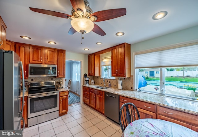 kitchen featuring ceiling fan, brown cabinets, a sink, appliances with stainless steel finishes, and backsplash