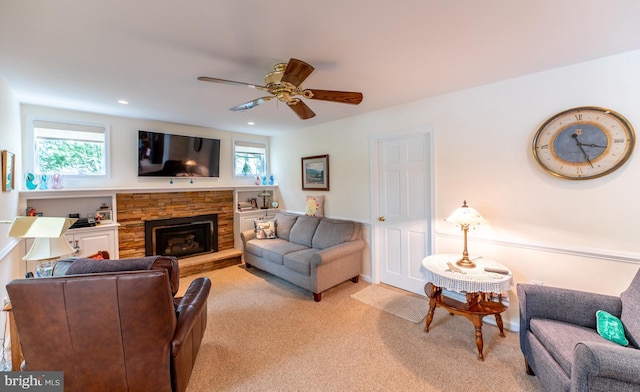 living area featuring a ceiling fan, a stone fireplace, recessed lighting, and light carpet