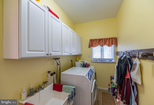 clothes washing area featuring cabinet space, baseboards, a sink, and washing machine and clothes dryer