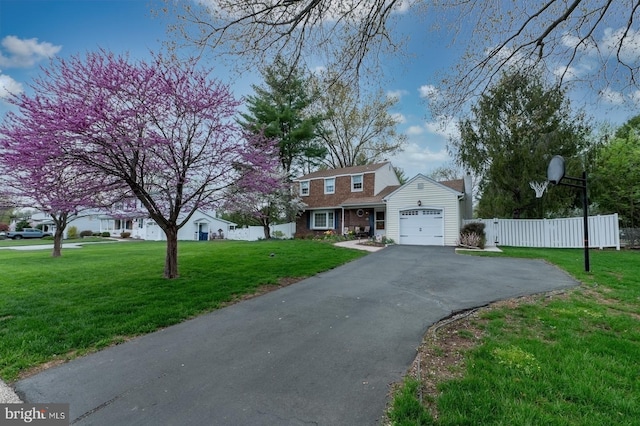 view of front of property with driveway, fence, a front lawn, and a garage